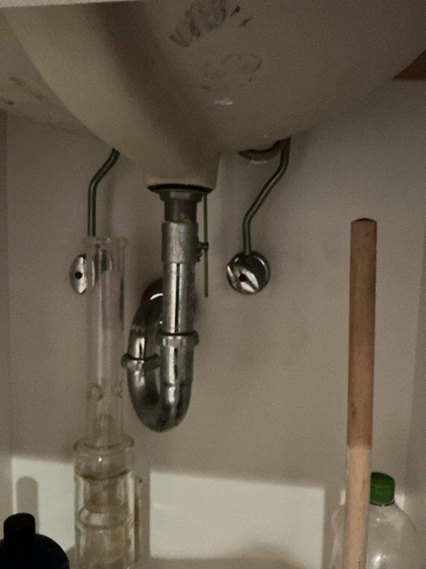 Responded to service call for faucet installation requiring two-person assistance. Upon arrival, confirmed that necessary parts were on-site and ready for installation. Assessed the existing under-sink plumbing configuration, which included a chrome P-trap assembly, supply lines, and shut-off valves in functional condition. Prepared work area by placing catch bucket beneath drain assembly to protect cabinetry and contain any residual water during installation process. Documented pre-installation and post-installation conditions of plumbing connections and cabinet interior. Work completed successfully with all components properly secured and tested for proper drainage and water flow.