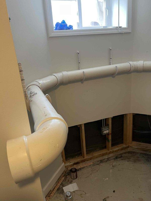 Completed main line drain and sewer installation requiring interior wall access and new PVC piping configuration. Opened wall cavity to expose existing framing and insulation, then installed vertical drainage pipe through the wall structure with proper fittings and elbow connections. Routed additional PVC piping horizontally across the room using metal mounting brackets secured to wall surfaces, ensuring proper slope and support for drainage flow. All pipe joints were properly fitted and secured according to code requirements for residential plumbing systems.