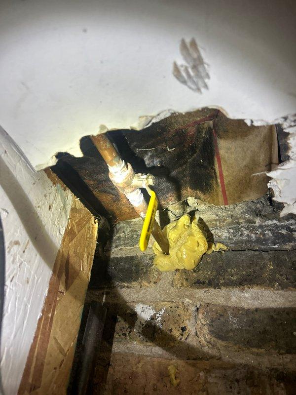 Responded to report of interior leak originating from outdoor spigot supply line. Upon inspection, identified active water leak in copper supply piping located within interior wall cavity behind exterior hose bib. Accessed affected area through interior access point, revealing compromised pipe section with visible water damage to surrounding wooden framing members and insulation material. 

Isolated water supply to outdoor spigot and assessed extent of damage to supply line and structural components. Documented existing conditions showing water-stained and deteriorated framing, compromised insulation, and active leak point in copper piping. Exterior inspection confirmed hose bib mounted to brick facade with standard garden hose connection remaining functional at fixture point.

Provided estimate for complete repair including replacement of damaged copper supply line section, reinstallation of water supply to exterior spigot, removal and replacement of compromised insulation material, a