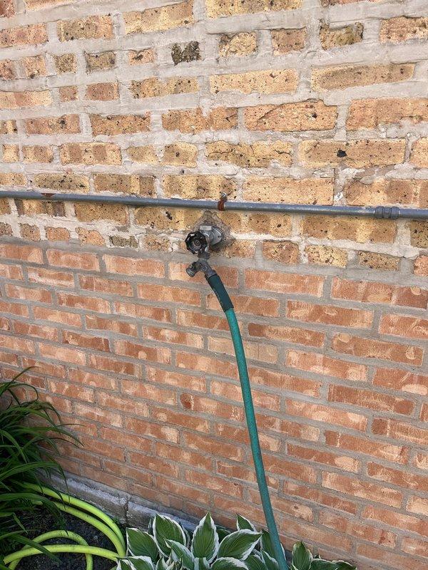 Responded to report of interior leak originating from outdoor spigot supply line. Upon inspection, identified active water leak in copper supply piping located within interior wall cavity behind exterior hose bib. Accessed affected area through interior access point, revealing compromised pipe section with visible water damage to surrounding wooden framing members and insulation material. 

Isolated water supply to outdoor spigot and assessed extent of damage to supply line and structural components. Documented existing conditions showing water-stained and deteriorated framing, compromised insulation, and active leak point in copper piping. Exterior inspection confirmed hose bib mounted to brick facade with standard garden hose connection remaining functional at fixture point.

Provided estimate for complete repair including replacement of damaged copper supply line section, reinstallation of water supply to exterior spigot, removal and replacement of compromised insulation material, a