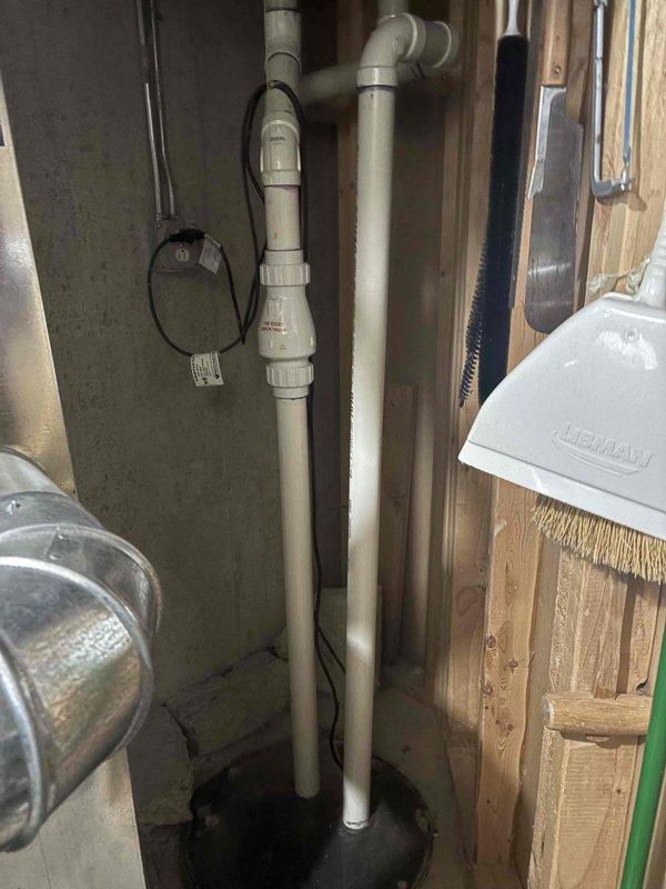 Responded to report of sump pump leaking when washing machine drains. Inspected sump pump system, discharge piping, and battery backup unit in basement utility area. Evaluated washing machine drain connection to identify source of water intrusion into sump basin. Assessed condition of existing battery backup system and verified proper operation of pump float switch and check valve assembly.
