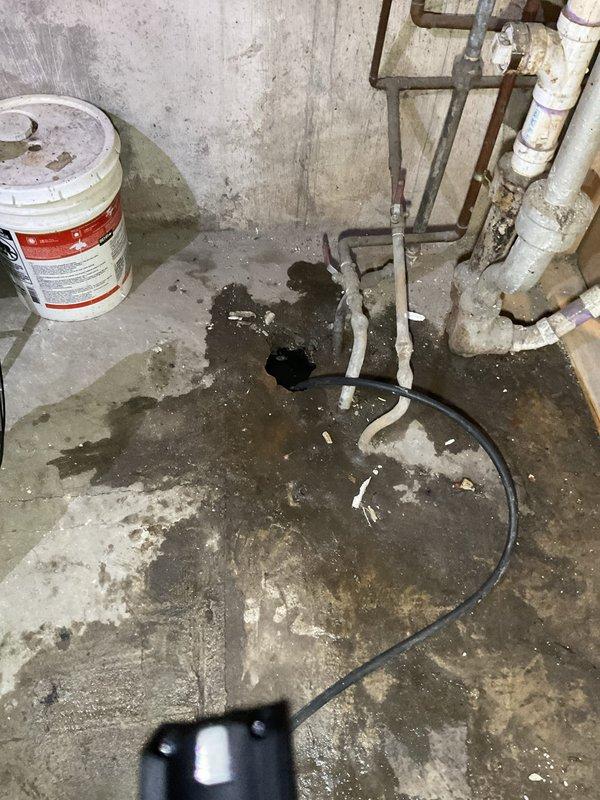 Performed sewer line rodding and camera inspection for residential property in preparation for home sale. Technician utilized motorized drain cleaning equipment with cable drum to clear the main sewer line, accessing the system through an exterior cleanout in the backyard. Following the mechanical cleaning, a comprehensive video camera inspection was conducted to document the interior condition of the sewer line and verify proper flow. Equipment setup included positioning the power rodding machine on the concrete patio area with appropriate safety protocols. Interior basement plumbing connections and floor drain access points were inspected as part of the comprehensive evaluation. Documentation completed through photographic evidence of equipment deployment and work areas to support the real estate transaction requirements.