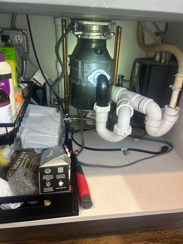Installed customer-supplied water treatment system under kitchen sink, integrating the filtration unit with existing plumbing configuration that includes garbage disposal, copper supply lines, and PVC drain assembly. Connected system to cold water supply line and verified proper operation of all components including disposal, P-trap drainage, and new filtration unit with flexible discharge line.