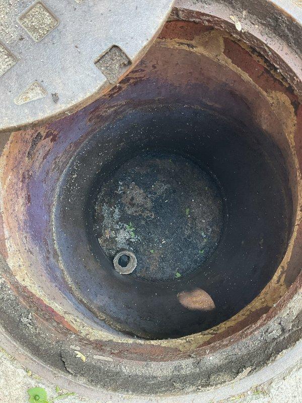 Completed catch basin cleaning and ejector pit maintenance at residential property. Serviced floor drain system with rusted metal collar and removed accumulated sediment and debris from pit containing standing water. Performed routine maintenance on ejector pit system connected to white PVC plumbing infrastructure in unfinished basement area. Inspected multiple corroded floor flanges at pipe penetrations through concrete slab and verified proper drainage function. System operational upon completion with all drainage pathways clear.