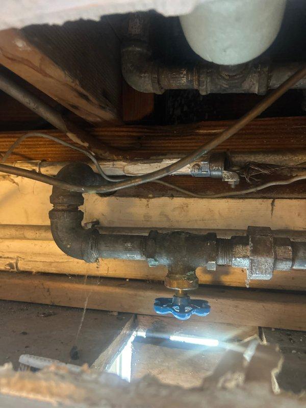 Responded to water leak investigation in basement bathroom area. Located active leak at soldered copper pipe joint connection on vertical riser serving bathroom fixtures. Inspected surrounding copper supply lines, fittings, and solder joints in crawl space area beneath bathroom. Documented condition of plumbing system including copper piping with visible oxidation, galvanized steel lines with shut-off valve, and mixed plumbing infrastructure. Identified failed solder joint as source of water intrusion. Photographed leak location and affected plumbing components for repair estimate documentation.