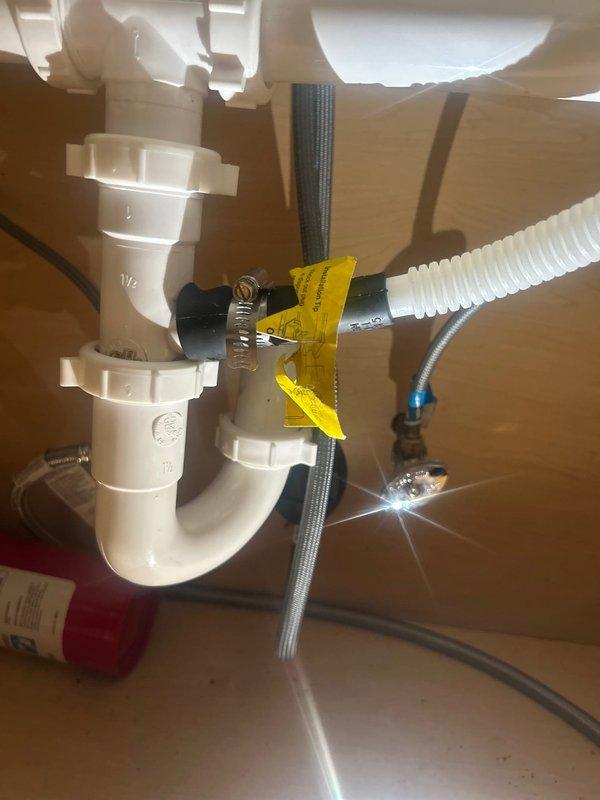 Responded to service call for dishwasher leak concern and installation verification. Upon inspection, examined under-sink plumbing connections and dishwasher drain line installation. Verified proper P-trap configuration, drain line connections, and water supply lines. Documented existing plumbing setup including PVC drain assembly, flexible discharge hose connections, and supply line installations with photographic evidence for customer records.