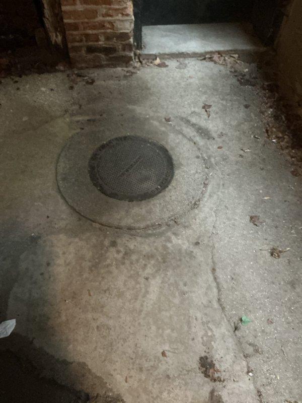 Responded to emergency service call for deteriorating catch basin showing structural failure. Upon inspection, found catch basin cover embedded in damaged concrete floor with significant surface deterioration, cracking, and water damage evident throughout surrounding area. Exterior assessment revealed severe structural compromise with irregular cracks, heavy moss and algae growth indicating chronic moisture infiltration, and complete deterioration of adjacent surfaces. Documented extensive damage to both interior and exterior catch basin components requiring full replacement due to caving conditions and safety concerns.