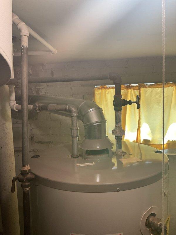 Completed installation of new tanked water heater in basement utility area. Removed existing water heater unit and installed replacement cylindrical tank model with proper connections including hot and cold water supply lines, pressure relief valve with discharge piping, and all required shut-off valves. Connected copper supply piping to unit with brass fittings and installed PVC venting system through existing infrastructure. Verified all connections for proper sealing, tested unit operation, and confirmed adequate clearances per manufacturer specifications and local code requirements.