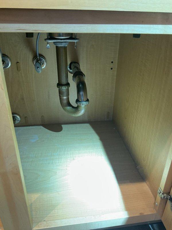 Responded to a main drain cleanout service call in a highrise building where multiple units experienced simultaneous drainage issues affecting kitchen sinks due to a clog in the shared waste line. Upon inspection, found significant accumulation of coffee grounds and debris in the double-basin kitchen sink, accessed the P-trap assembly beneath the sink cabinet, and successfully cleared the blockage to restore proper drainage function for both affected units.