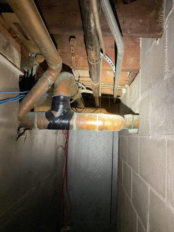 Responded to report of water leaking from toilets into basement area. Upon inspection, accessed crawl space and identified corroded cast iron waste pipe with visible rust deterioration and previous temporary repairs using black tape. The compromised pipe section showed significant moisture damage and structural degradation, indicating active leak allowing wastewater to escape into basement. Documented existing conditions including deteriorated piping, temporary patch attempts, and water damage patterns. Advised customer that affected section of waste line requires replacement to resolve leak and prevent further water intrusion and potential structural damage to basement area.