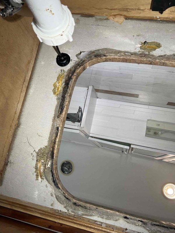 Completed installation of undermount kitchen sink with removal and replacement of deteriorated bathroom sink showing extensive water damage, mold growth, and compromised sealant around perimeter. Addressed moisture infiltration issues, replaced damaged substrate materials, and ensured proper waterproofing and drainage connections. Documented pre-existing conditions including water staining and structural deterioration for comprehensive renovation work in bathroom area.