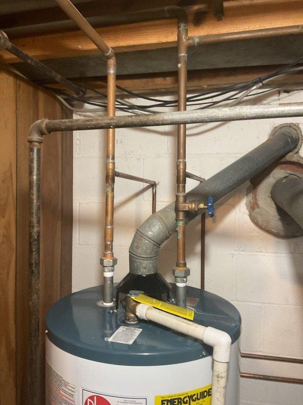 Provided comprehensive estimate for preemptive replacement of existing Rheem 50-gallon tall gas water heater with new Rheem Performance 50-gallon tall gas water heater in basement of home constructed in 1967-1969. Estimate includes complete removal and disposal of existing unit, installation of new water heater with all necessary copper piping connections, shut-off valves, and gas line hookup, plus all required materials, labor, permits, and full compliance with municipal code requirements and inspection. Current installation shows standard residential configuration with copper supply lines, appropriate venting through existing ductwork, and connections to overhead plumbing system in unfinished basement utility area.