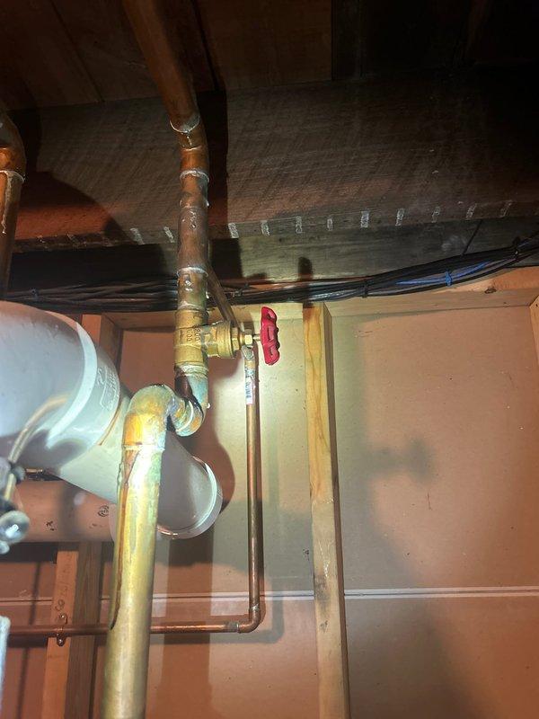 Responded to service call for water heater leaking from top with no hot water available. Upon inspection, found aging water heater installed in 2008 showing signs of deterioration at top connections. Observed corroded copper piping with significant oxidation and patina formation throughout the plumbing system. Documented existing infrastructure including brass valves with red handles, PVC drainage piping, and basement mechanical installation. Assessed condition of water heater connections, supply lines, and associated plumbing components to provide comprehensive estimate for water heater replacement and necessary piping modifications.