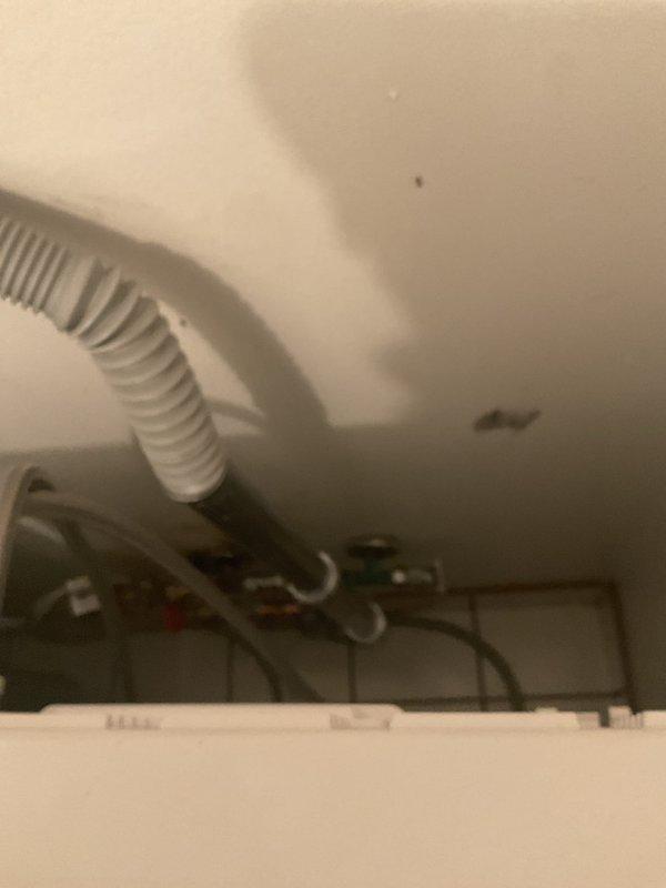 Responded to service call for washer not receiving hot water at 50-year-old condominium unit. Upon inspection, assessed water heater connections and supply line configuration in utility closet. Examined existing shutoff valves, flex lines, and plumbing connections at water heater to diagnose hot water supply issue affecting washing machine. Documented installation with photos showing water heater underside, brass fittings, braided stainless steel flex lines, and valve assembly for service records and potential repair recommendations.