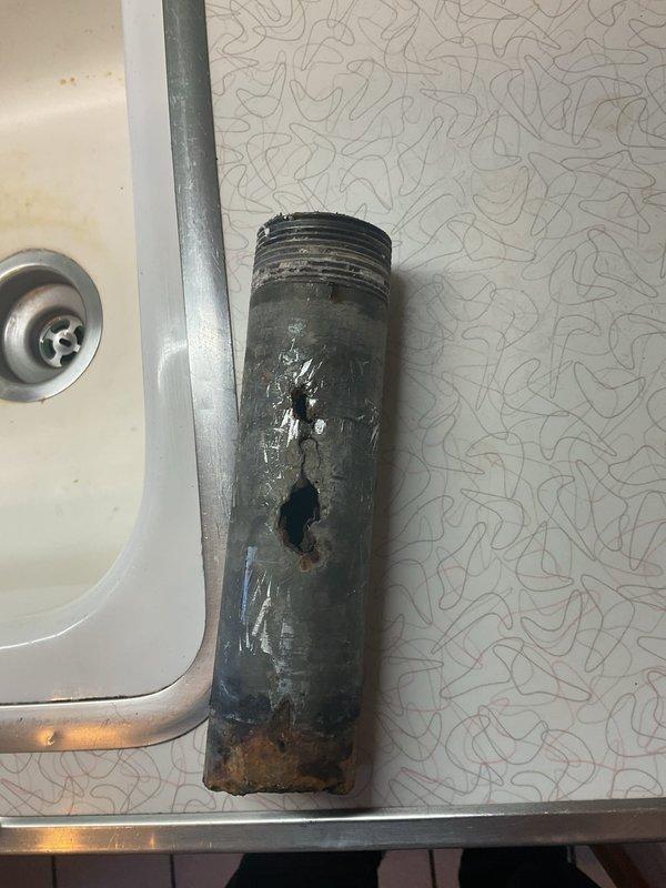 Responded to kitchen sink drainage system failure caused by severely corroded galvanized nipple and leaking J-trap assembly. Removed and replaced deteriorated galvanized nipple that had developed perforation due to extensive rust and corrosion. Repaired leaking J-trap connection to restore proper drainage function and eliminate water leakage beneath sink.