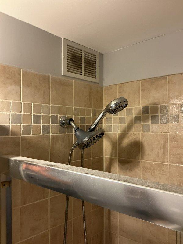 Responded to no hot water complaint in shower/tub area. Upon inspection, found exposed water supply outlets at tub level with open pipe ends, indicating incomplete fixture installation or recent removal. Assessed dual-head shower system with flexible hose connection mounted on tiled wall. Verified proper installation of safety grab bars and examined existing plumbing infrastructure including wall-mounted supply lines and drainage connections to diagnose hot water delivery issue.
