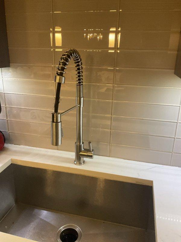 Responded to a kitchen sink leak that had been present for approximately three weeks, with water leaking onto the counter surface rather than beneath the sink. Successfully installed a new commercial-style pull-down kitchen faucet with spring coil neck and spray head functionality to resolve the leaking issue. Verified proper installation, tested all connections for leaks, and confirmed the garbage disposal and associated plumbing components beneath the sink remained properly connected and functional following the faucet replacement.