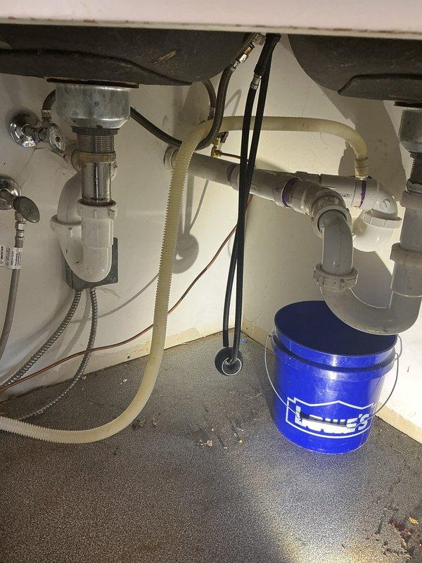 Completed residential drain and sewer estimate for kitchen plumbing system. Inspected dual-basin sink configuration with existing P-trap assemblies, drainage connections, and water supply lines. Documented current plumbing layout including white PVC drain piping, basket strainers, and flexible supply connections beneath kitchen sink cabinet for estimate preparation purposes.