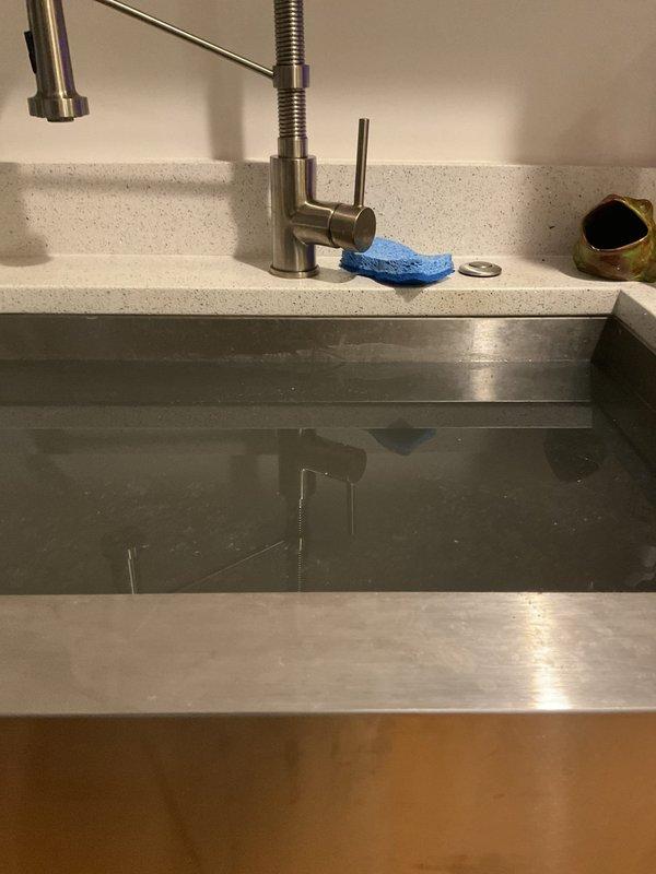 Responded to service call regarding dirty water issue at kitchen sink. Upon inspection, examined the undermount stainless steel sink, faucet assembly, and associated plumbing connections beneath the countertop. Investigated the under-sink cabinet area, inspecting the garbage disposal unit, P-trap configuration, water supply lines, and drain connections for potential sources of contamination or sediment causing discolored water at the fixture. Documented existing plumbing conditions with photographic evidence for estimate purposes.