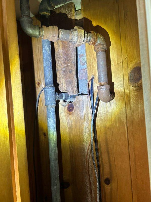 Responded to burst outdoor faucet line requiring complete replacement. Removed existing damaged copper supply line and installed new frost-proof outdoor spigot with proper drainage capability to prevent future freeze damage. Added secondary ball-valve shut-off inside the structure for improved isolation and maintenance access, addressing the absence of interior shut-off controls in this 1961 construction. Upgraded piping configuration from wall-mounted copper to code-compliant installation with galvanized vertical supply lines secured to wall framing. Routed new supply lines through interior wall cavity with proper insulation to protect against temperature extremes. All connections pressure-tested and verified for proper operation of both interior shut-off valve and exterior frost-proof spigot.