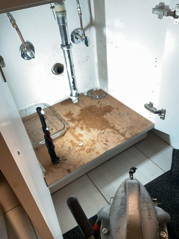 Responded to slow-draining bathroom sink in garden unit of century-old building. Upon arrival, confirmed homeowner had already cleared P-trap without resolving issue, indicating blockage located within wall cavity. Disassembled and inspected P-trap assembly and drain connections under sink to verify proper flow and rule out additional obstructions in accessible plumbing. Placed collection container under drain assembly to catch water during diagnostic work. Documented existing water damage on cabinet floor and evidence of previous leakage. Due to blockage location within wall and age of plumbing system, recommended follow-up assessment with drain camera or potential wall access to locate and clear obstruction in drain line.