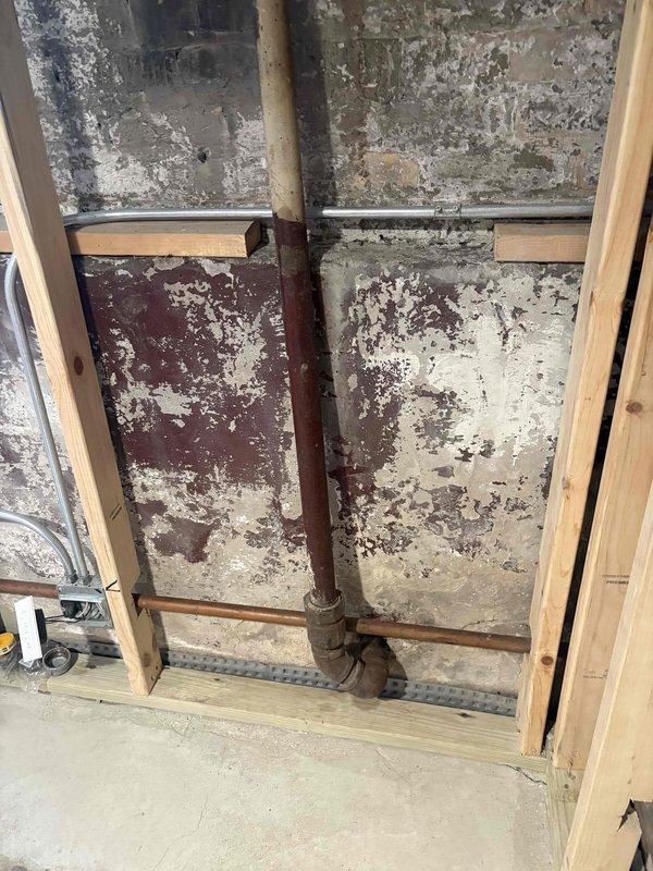 Responded to service call for broken outdoor spigot and removal of old gas line. Upon inspection, accessed crawl space beneath structure to assess plumbing infrastructure and locate deteriorated piping. Identified rusted waste pipe with corroded elbow joint and compromised supply lines requiring attention. Removed obsolete gas line from premises as requested, ensuring proper capping and safety protocols. Addressed outdoor spigot malfunction by replacing damaged components and securing new fixture to exterior wall. Documented existing conditions including spray foam insulation, structural supports, and deteriorated wall sections for reference.