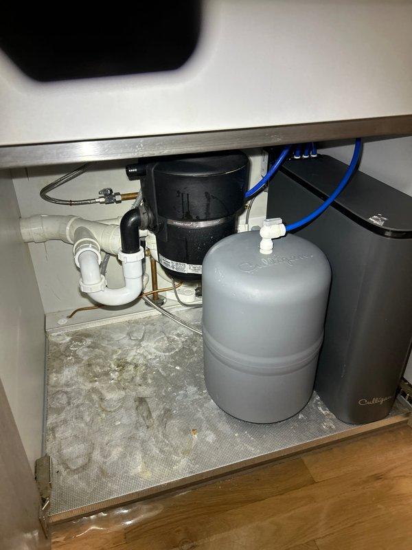 Responded to intermittent leak detection under kitchen sink. Upon inspection, identified compromised connection on braided flexible supply line feeding the reverse osmosis filtration system. Tightened supply line fitting and verified all connections to the RO tank, disposal unit, and P-trap assembly for proper seal integrity. Cabinet liner showed evidence of previous water accumulation, confirming intermittent leak pattern. All plumbing components tested and secured; no active leaks detected upon completion.