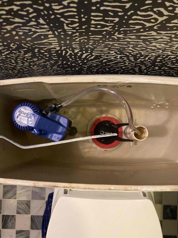 Completed toilet tank fixture installation including replacement of fill valve assembly and flapper valve mechanism. All internal tank components were properly installed and tested for proper operation, with water supply connections secured and verified leak-free.