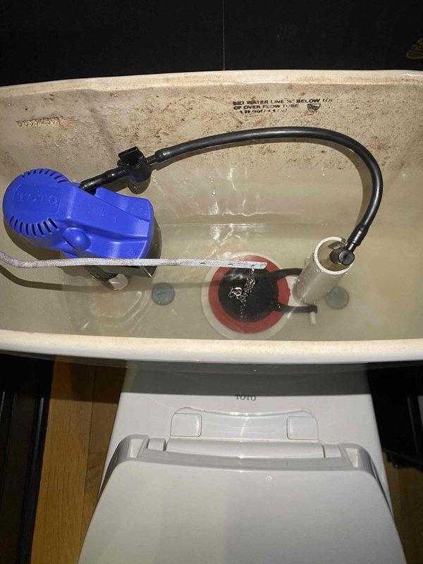 Completed toilet tank fixture installation including replacement of fill valve assembly and flapper valve mechanism. All internal tank components were properly installed and tested for proper operation, with water supply connections secured and verified leak-free.