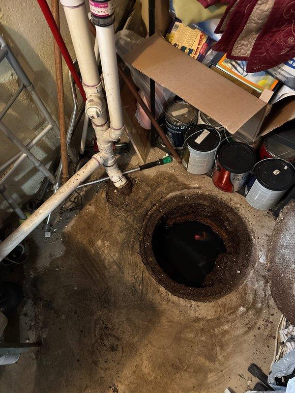 Responded to emergency call for basement utility sink flooding with black sewage backup in 50-year-old residential property. Upon arrival, found both sides of double utility sink experiencing repeated sewage overflow that had returned after being drained earlier in the day, with potential occurrence during homeowner's week-long absence.

Accessed main drain cleanout located in basement floor, which displayed significant corrosion and deterioration with heavy rust buildup around the opening edges. Cleanout contained standing dark sewage water, indicating main line blockage. Performed comprehensive drain cleaning of main sewer line using professional augering equipment to remove obstruction and restore proper drainage flow. Cleared blockage successfully, allowing sewage to drain from utility sink and main line. Verified proper drainage function through testing and confirmed no backup or slow drainage remained. Documented existing condition of severely corroded cleanout access point for h