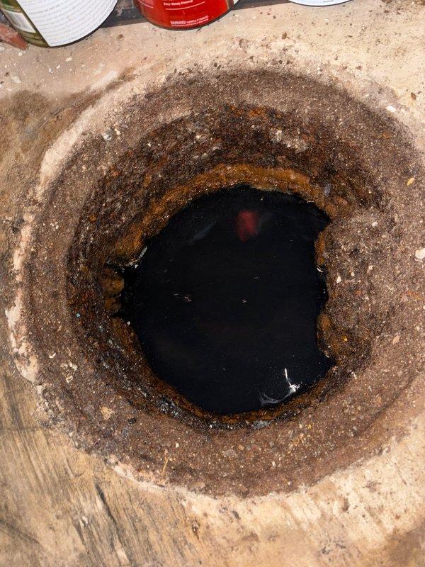 Responded to emergency call for basement utility sink flooding with black sewage backup in 50-year-old residential property. Upon arrival, found both sides of double utility sink experiencing repeated sewage overflow that had returned after being drained earlier in the day, with potential occurrence during homeowner's week-long absence.

Accessed main drain cleanout located in basement floor, which displayed significant corrosion and deterioration with heavy rust buildup around the opening edges. Cleanout contained standing dark sewage water, indicating main line blockage. Performed comprehensive drain cleaning of main sewer line using professional augering equipment to remove obstruction and restore proper drainage flow. Cleared blockage successfully, allowing sewage to drain from utility sink and main line. Verified proper drainage function through testing and confirmed no backup or slow drainage remained. Documented existing condition of severely corroded cleanout access point for h