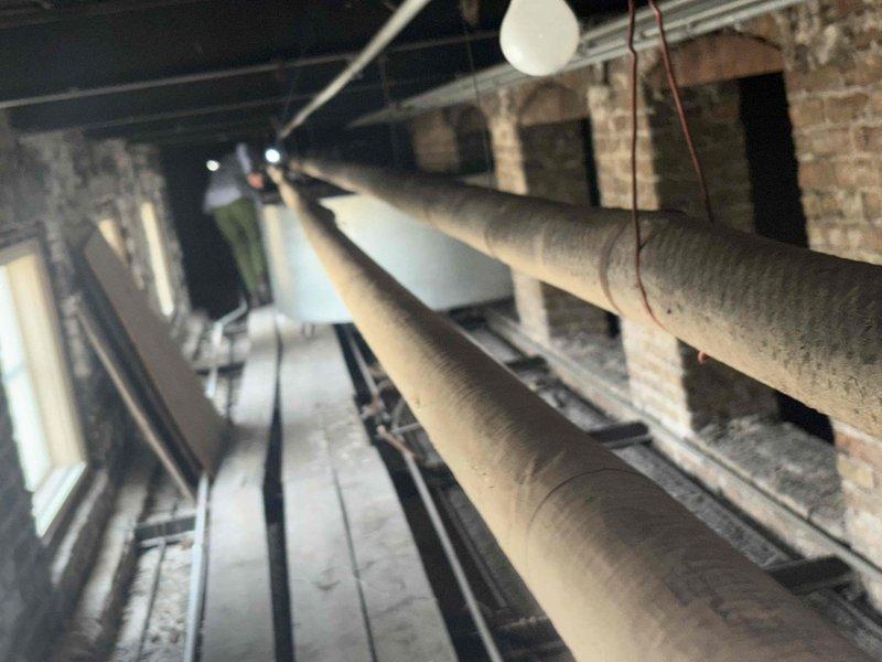 Conducted comprehensive site assessment of commercial building's deteriorating galvanized riser pipe system located in fourth-floor crawl space. Evaluated approximately 100-150 linear feet of 1" to 1.5" galvanized piping that branches into four separate stacks, documented existing conditions through photographic evidence showing exposed mechanical space with insulated ductwork, brick masonry construction, and crawl space areas with spray foam insulation between joists. Prepared detailed estimate for complete replacement of degraded galvanized piping system to restore proper functionality and prevent future failures.