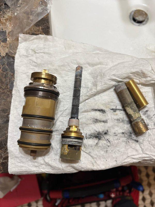 Removed and replaced defective shower valve cartridge in bathtub fixture. The original cartridge showed significant mineral buildup and corrosion, causing operational issues. Disassembled brass shower fixture assembly, extracted old cartridge, and installed new replacement cartridge to restore proper water flow and temperature control functionality.