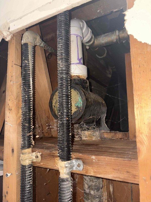 Responded to emergency plumbing service call for burst pipe repair in residential basement living area. Created ceiling and wall access points to reach compromised drain system components. Replaced severely corroded metal drain trap assembly showing significant oxidation and mineral buildup with new PVC P-trap configuration. Applied proper primer and secured all connections to code. Addressed water damage concerns by exposing affected structural areas including ceiling joists and wall cavities to ensure proper assessment and drying. Rerouted and secured existing flexible conduits during repair process. Verified all drain connections for proper flow and seal integrity upon completion.