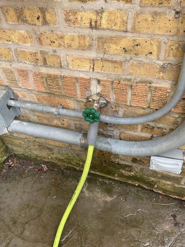 Responded to report of exterior hose bib leaking inside the home. Upon arrival, inspected the outdoor spigot assembly mounted on brick exterior wall and traced water intrusion to failed valve stem packing. The existing galvanized piping showed significant corrosion and weathering consistent with age and outdoor exposure. Disassembled the gate valve assembly, replaced deteriorated packing material and stem washers, reassembled unit, and tested operation under full pressure to confirm leak was eliminated with no interior water penetration.