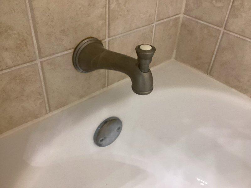 Responded to callback for non-functioning shower diverter in primary bathroom that remained inoperative following previous service visit. Inspected bathtub spout assembly with oil-rubbed bronze finish and diverter mechanism mounted on tile wall. Assessed plumbing connections and water flow redirection system between tub spout and showerhead. Documented existing conditions and fixture configuration for resolution of persistent diverter malfunction.