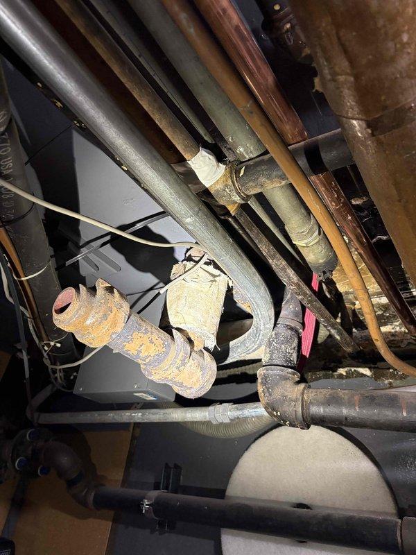 Conducted comprehensive site assessment for 2-inch gas line re-piping project in basement utility area. Evaluated existing piping infrastructure, which included aging copper lines showing significant corrosion and patina, black PVC pipes, and various diameter gas lines with makeshift repairs including tape-wrapped connections. Documented current condition of mechanical systems, noting deteriorated metal couplings with heavy rust oxidation, compromised pipe joints, and overall aging infrastructure requiring replacement. Photographed existing piping layout running vertically and diagonally through confined utility space, including proximity to HVAC equipment and structural elements. Assessed scope of work needed to remove and replace existing gas piping system with new 2-inch gas line installation, accounting for complex routing requirements and integration with existing mechanical systems. Provided detailed visual documentation and measurements for accurate pricing estimate.