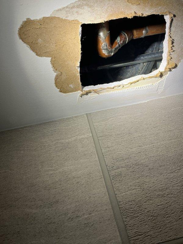 Responded to a ceiling leak complaint near the stairwell where a slow drip was identified on a 3/4" copper water pipe. Upon inspection, shut down the main water supply to the house and enlarged the existing ceiling access opening to expose the full extent of the leak. Removed the damaged section of 3/4" copper water piping, including a 90-degree elbow and 45-degree elbow that showed significant corrosion and mineral deposits. Installed new 3/4" copper pipe and fittings to replace the compromised section, restoring full water pressure and eliminating the leak. All new pipework was pressure tested and verified leak-free before restoring water service to the home. Ceiling repair remains the responsibility of the property owner or designated contractor.