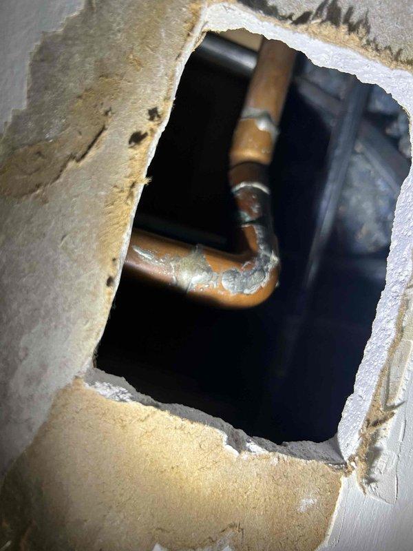 Responded to a ceiling leak complaint near the stairwell where a slow drip was identified on a 3/4" copper water pipe. Upon inspection, shut down the main water supply to the house and enlarged the existing ceiling access opening to expose the full extent of the leak. Removed the damaged section of 3/4" copper water piping, including a 90-degree elbow and 45-degree elbow that showed significant corrosion and mineral deposits. Installed new 3/4" copper pipe and fittings to replace the compromised section, restoring full water pressure and eliminating the leak. All new pipework was pressure tested and verified leak-free before restoring water service to the home. Ceiling repair remains the responsibility of the property owner or designated contractor.