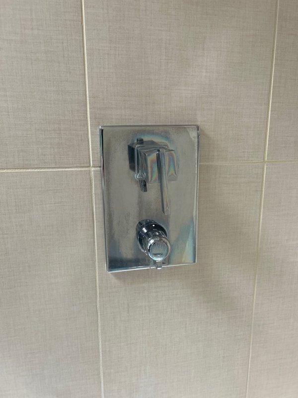 Responded to service call for dripping shower head in residential bathroom. Upon inspection, identified leak originating from the shower control valve assembly. Examined the dual-control chrome fixture mounted in tiled shower enclosure, noting water seepage from the upper lever handle mechanism. Assessed main water supply lines and shutoff valves in basement utility area to ensure proper system pressure and isolation capability. Repaired the faulty shower valve cartridge, replacing worn internal seals causing the persistent drip. Tested the fixture operation post-repair to verify proper flow control and complete shutoff without leakage. System restored to full functionality with no further dripping observed.