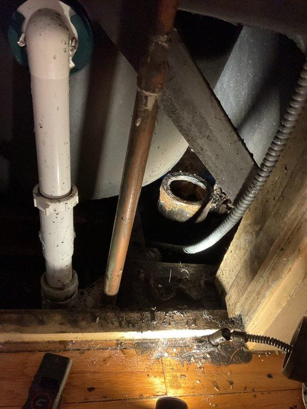 Responded to a bathtub drain clog on the middle floor of a century-old residence where the blockage had persisted for approximately five days. Accessed the drain system through the under-sink area, inspecting the existing plumbing infrastructure which consisted of white PVC drain lines with teal couplings and copper supply lines showing age-appropriate patina and minor corrosion at joints. Assessed the drain assembly and determined the clog location within the drainage system. Successfully cleared the obstruction using appropriate drain cleaning methods, restoring proper water flow to the bathtub. Verified all connections remained secure and tested the drain for proper function before completing the service call.