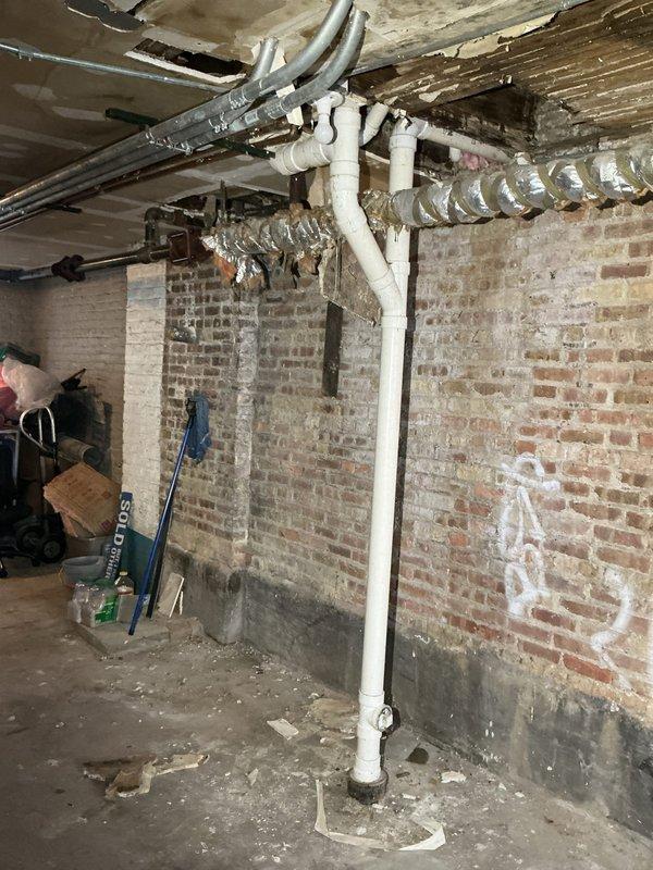 Responded to a recurring toilet backup issue where previous plumbers provided conflicting diagnoses regarding the cause. Performed comprehensive diagnostic assessment of the drainage system in the basement area to determine the actual source of the backup, examining both the possibility of foreign object obstruction (wipes/tampons) and structural pipe damage from tree root intrusion. Documented conditions of exposed plumbing lines and drain system for further evaluation and recommendation of appropriate corrective action.