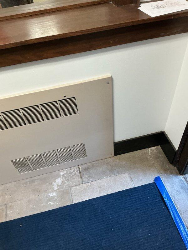 Responded to priority water leak located underneath stone tile flooring in office area. Upon arrival, conducted thorough visual inspection revealing extensive water damage and mineral deposits across gray tile flooring, with white residue patterns indicating active moisture intrusion beneath the surface. Documented damage conditions with photographic evidence showing affected areas concentrated around HVAC unit and floor corners. Protected work area with floor covering to prevent further contamination during assessment.