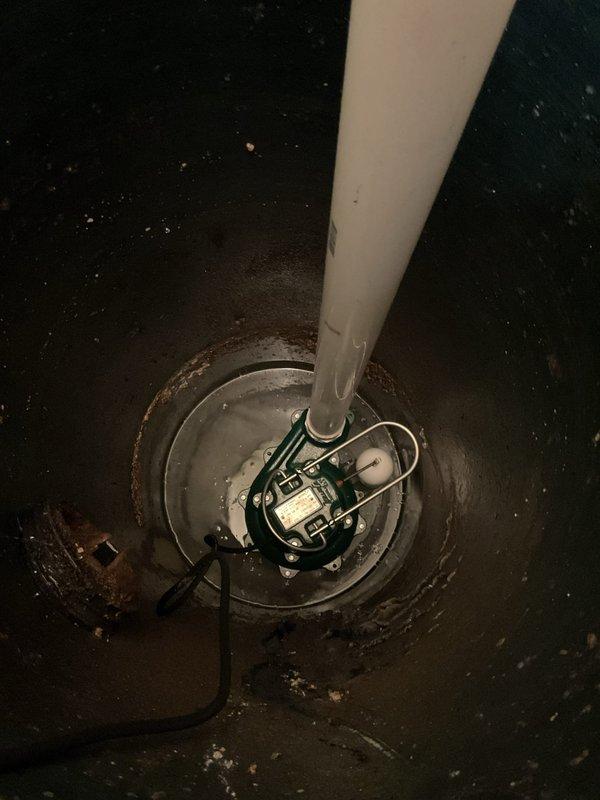 Completed installation of new sump pump system with dual basin configuration and PVC discharge piping. The system includes properly mounted pump unit with electrical connections, vertical discharge pipe assembly with appropriate fittings and elbows, and floor-mounted basins secured in concrete for optimal drainage performance.