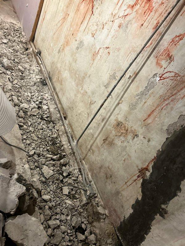 Completed plumbing repair requiring extensive demolition work to access compromised piping systems. Removed deteriorated concrete and plaster from basement wall to expose vertical conduits showing signs of water damage and corrosion. Debris removal and site preparation performed for upcoming pipe replacement and wall restoration work.
