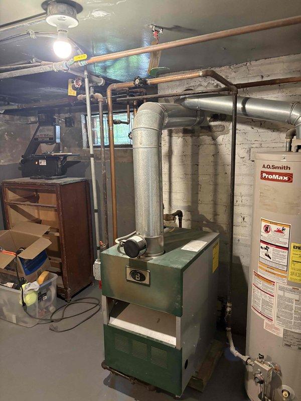 Conducted on-site assessment for water heater and boiler relocation in residential basement. Evaluated existing A.O. Smith water heater and green metal boiler unit currently positioned in utility area, documenting placement constraints and available space for potential reconfiguration. Photographed existing mechanical systems, including copper supply lines, exhaust venting, gas connections, and ductwork to determine scope of work required for relocation. Discussed options with homeowner for relocating equipment to maximize usable basement space and explored alternative configurations for improved layout efficiency.