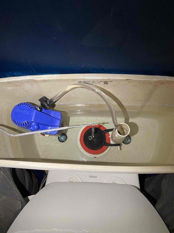 Responded to service call for toilet tank component inspection and documentation. Upon arrival, performed thorough visual assessment of toilet tank interior mechanisms including fill valve assembly, flush valve, and flapper system. Noted presence of blue float-style fill valve with standard operational components and red rubber flapper valve with chain assembly in proper working position. Documented water discoloration and minor mineral deposits on porcelain surfaces indicating normal wear patterns. Captured detailed photographic documentation of tank interior components and configuration for scheduling follow-up installation work. All observations recorded for coordination with main line drain and sewer installation project.
