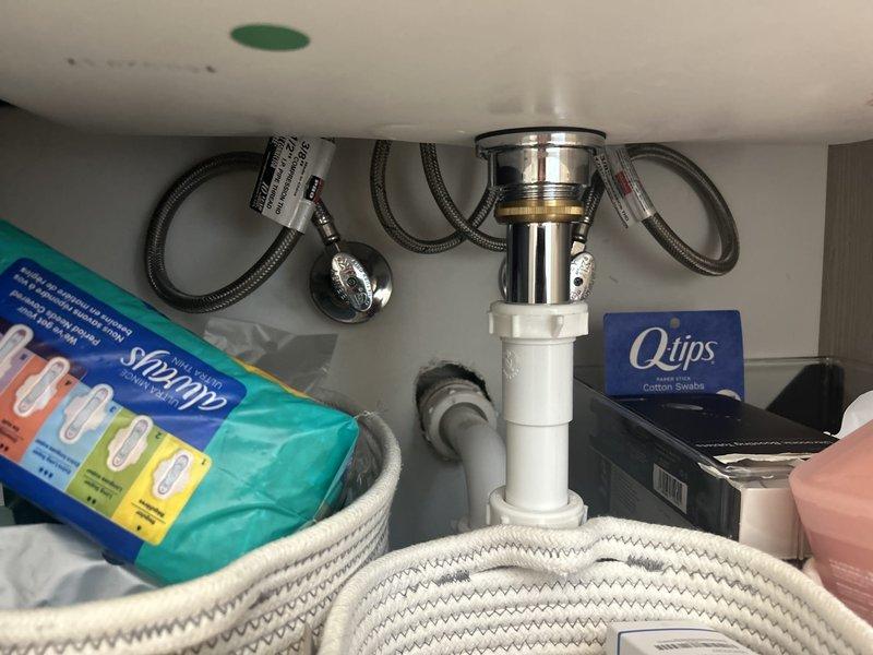 Installed new chrome garbage disposal unit beneath kitchen sink with proper mounting and connection to existing drainage system. Connected flexible braided metal supply lines and white PVC discharge piping to ensure proper water flow and waste removal. Verified all connections are secure and leak-free, with disposal unit properly mounted and operational beneath the sink basin.