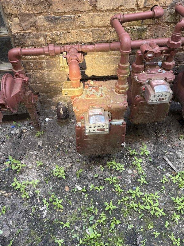 Responded to no hot water complaint affecting entire building in century-old residential property. Upon arrival, accessed property using provided gate code and conducted comprehensive inspection of plumbing system and gas utility infrastructure. Documented existing gas meter installation and piping configuration serving the building, noting aged copper and steel piping with visible corrosion and weathering consistent with the structure's age. Assessed water heater functionality, gas supply connections, and distribution system to identify cause of hot water failure throughout building.