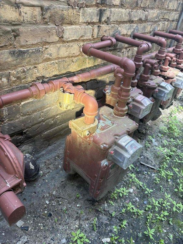 Responded to no hot water complaint affecting entire building in century-old residential property. Upon arrival, accessed property using provided gate code and conducted comprehensive inspection of plumbing system and gas utility infrastructure. Documented existing gas meter installation and piping configuration serving the building, noting aged copper and steel piping with visible corrosion and weathering consistent with the structure's age. Assessed water heater functionality, gas supply connections, and distribution system to identify cause of hot water failure throughout building.